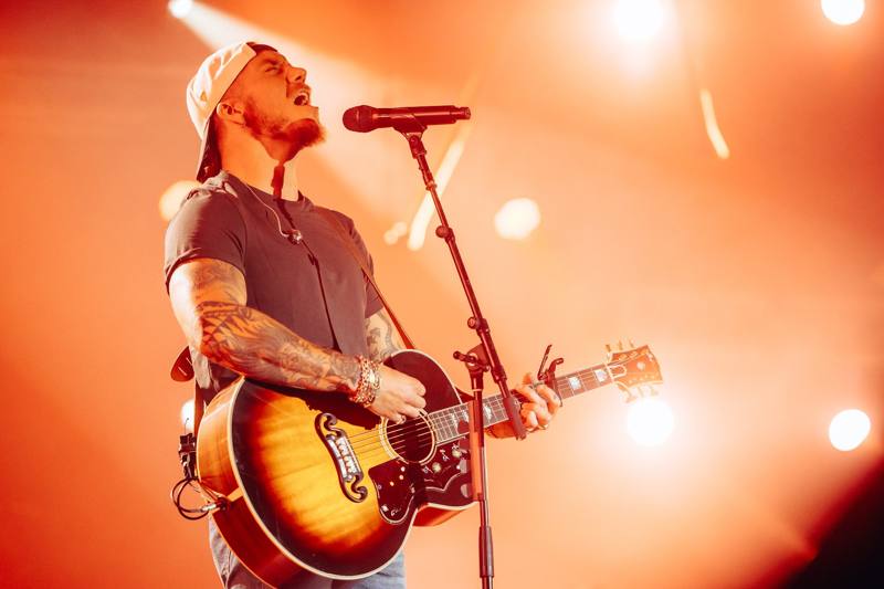 A worship artist singing and playing acoustic guitar on stage
