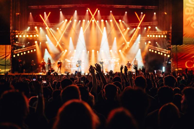 Main stage lit up in gold and orange light in front of the evening crowd