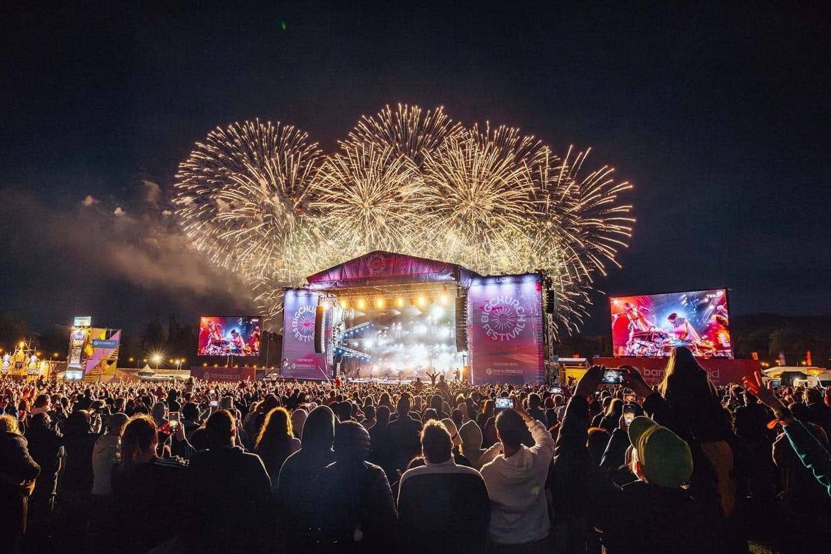 Gold fireworks over the Big Church Festival main stage at night, with the crowd holding phones up